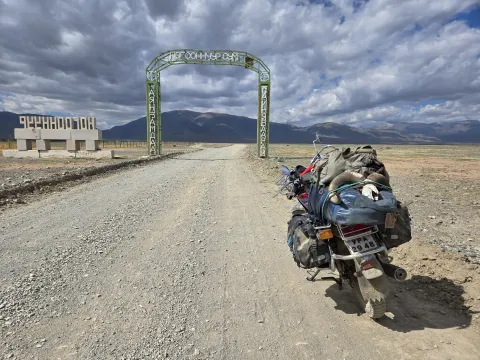 Motorcycle on dirt road with mountain ahead.